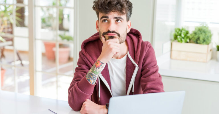 9401-man-with-tattoo-arm-at-laptop-looking-up-wond.jpg