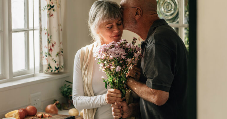 9228-senior-man-kissing-wife-holding-flowers-by-ki.jpg
