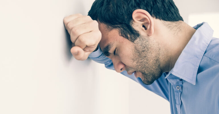 14211-man-concerned-with-head-against-wall-in-serio.jpg